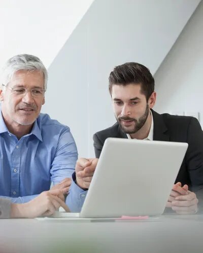 Jüngerer und älterer Mann schauen sich etwas am Laptop an