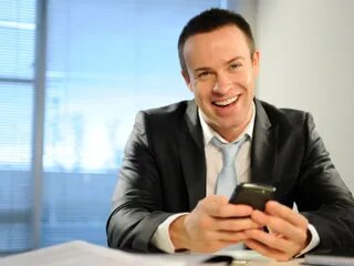 Lächelnder Mann im Anzug mit Smartphone in der Hand